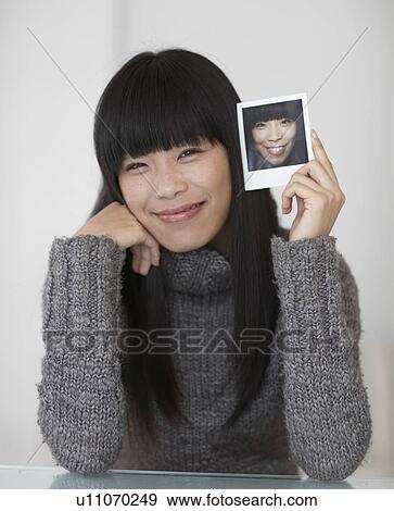 Stock Photo - Mid-Adult Woman Holding Photograph of Herself. Fotosearch