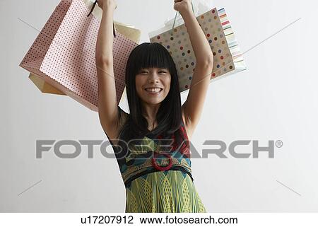 Stock Image - Mid Adult Woman Lifting Shopping Bags. Fotosearch