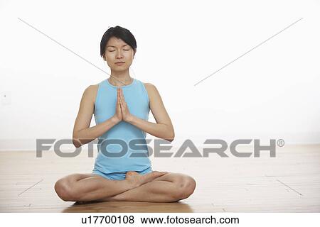 Stock Photo - Mid Adult Woman Meditating in Lotus Position. Fotosearch