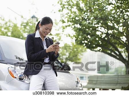 Mid-Adult Woman Text Messaging by Smart Car View Large Photo Image Stock Photo - Mid-Adult Woman Text Messaging by Smart Car. Fotosearch