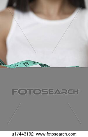 Stock Image - Tape Measure near Mid-Adult Woman. Fotosearch