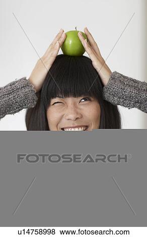 Stock Photo - Woman Balancing Single Apple on Head. Fotosearch