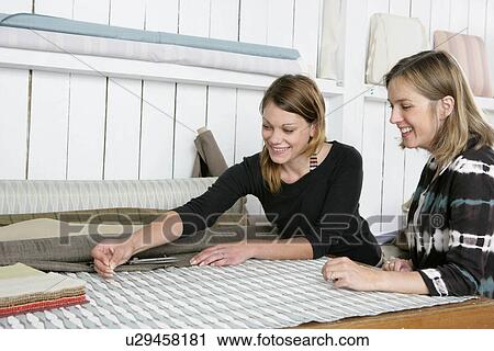 Stock Image - 2 women choosing fabrics. Fotosearch