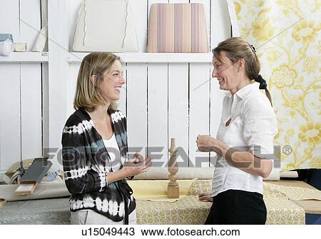 Stock Image - 2 women discussing project. Fotosearch