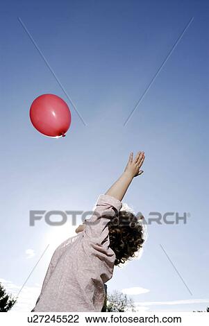 Stock Image - 3 years old girl throwing a balloon. Fotosearch