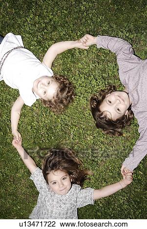 Stock Image - 3 young girls holding hands. Fotosearch