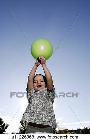 Stock Photo - 5 years old girl holding a balloon. Fotosearch