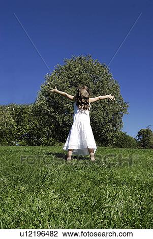 Stock Image - 5 years old girl standing by a tree. Fotosearch