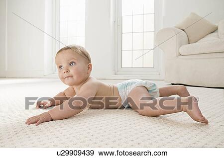 A baby lying on the lounge carpet. View Large Photo Image Stock Photo - A baby lying on the lounge carpet.. Fotosearch