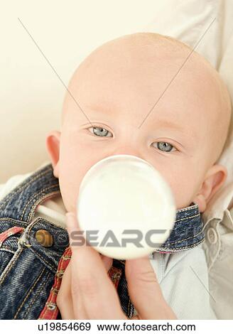 Stock Photo - A baby relaxed drinking a bottle of milk. Fotosearch