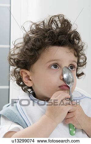 A boy holding a spoon on his nose. View Large Photo Image Picture - A boy holding a spoon on his nose.. Fotosearch