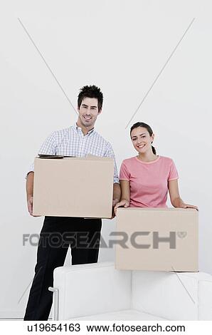 Stock Image - A couple holding cardboard boxes. Fotosearch