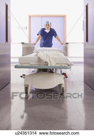Picture - A female doctor pushing a bed. Fotosearch