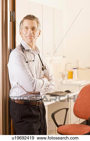 Stock Photo - A male doctor standing in his surgery. Fotosearch