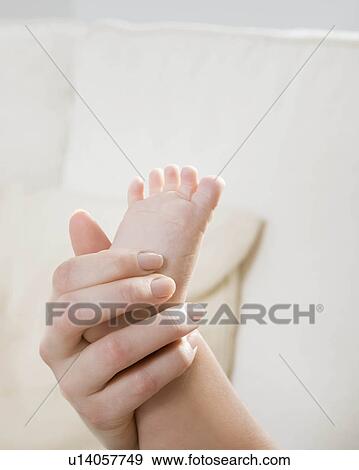 Stock Photo - A mother holding her child's foot.. Fotosearch