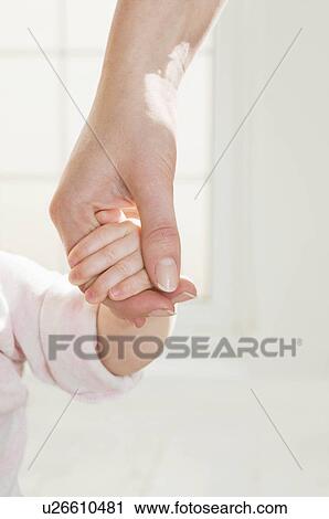 Stock Image - A mothers hand holding her baby's hand.. Fotosearch