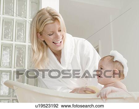 Stock Image - A mum bathing her baby girl.. Fotosearch