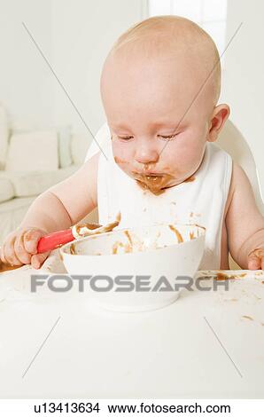 Picture - A portrait of a baby eating his food.. Fotosearch