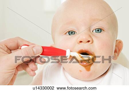 Stock Image - A portrait of a baby eating his food.. Fotosearch