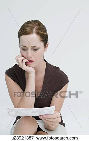A worried woman looking at a bill. View Large Photo Image Stock Photo - A worried woman looking at a bill.. Fotosearch