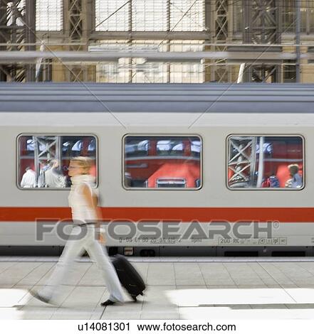 Stock Image - Blur of woman walking past train. Fotosearch