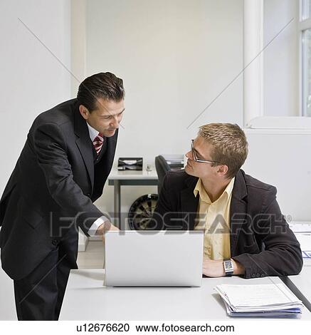 Boss looking at laptop with co-worker View Large Photo Image Stock Image - Boss looking at laptop with co-worker. Fotosearch