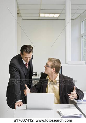 Boss looking at laptop with co-worker View Large Photo Image Stock Image - Boss looking at laptop with co-worker. Fotosearch