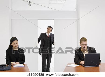 Stock Photography - Boss overlooking co-workers. Fotosearch