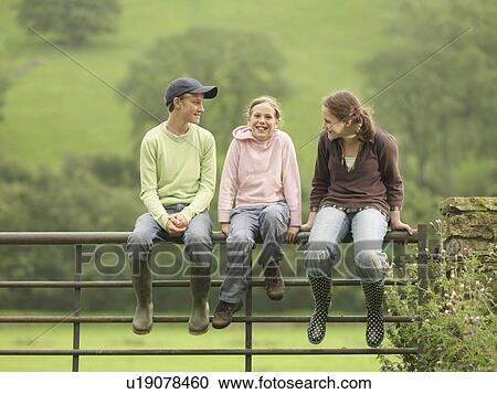 Stock Image - Boy And Girls Sitting On Fence. Fotosearch