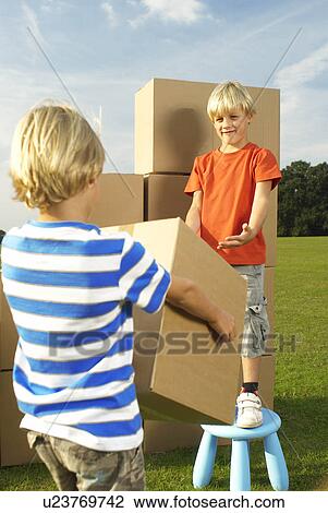 Stock Image - boy handing box to his brother. Fotosearch