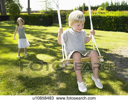 Boy on a swing, pushed by a girl View Large Photo Image Stock Image - Boy on a swing, pushed by a girl. Fotosearch