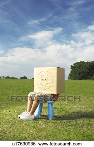 Stock Photograph - boy on stool with box on head. Fotosearch