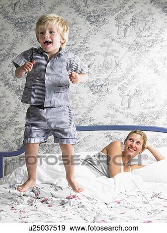 Stock Photo - Boy playing with his mother on the bed. Fotosearch