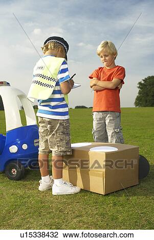 Stock Image - boy policeman booking boy driver. Fotosearch