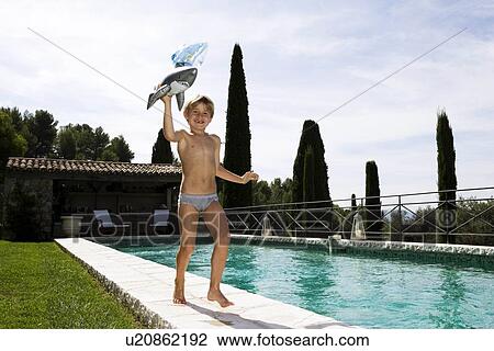 Stock Image - Boy running at swimming pool. Fotosearch