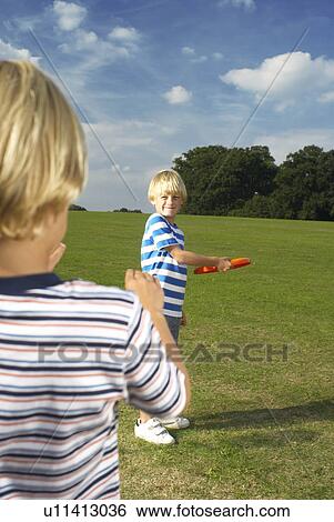 Stock Photograph - boy throwing frisbee to another boy. Fotosearch