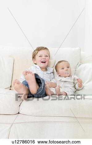Stock Photograph - Brothers sitting together on a sofa. Fotosearch