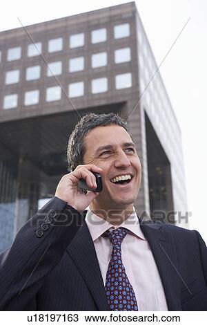 Stock Image - Business man using mobile phone outside. Fotosearch