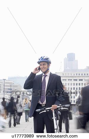 Stock Photo - Business man with bicycle & mobile phone. Fotosearch