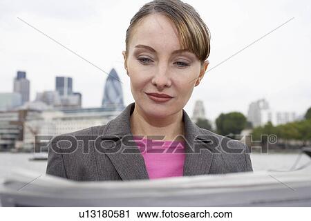Stock Image - Business woman reading newspaper outside. Fotosearch