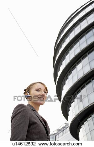 Stock Image - Business woman using bluetooth headset. Fotosearch