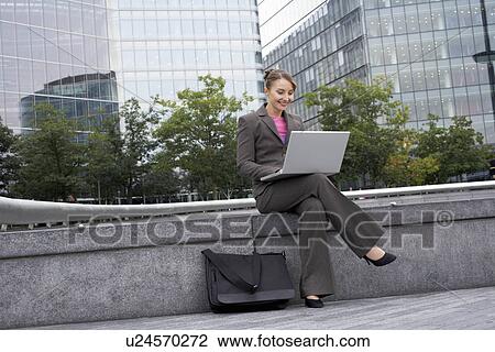 Stock Image - Business woman using laptop outside. Fotosearch