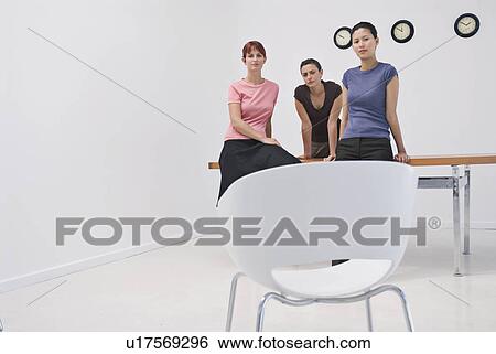 Stock Photograph - Business women sitting on a desk. Fotosearch