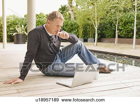 Stock Photo - Businessman looking at laptop outside. Fotosearch