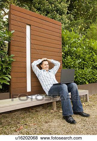 Stock Photo - Businessman relaxing with laptop outside. Fotosearch
