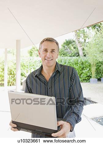 Stock Image - Businessman sitting outside smiling.. Fotosearch