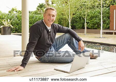 Businessman sitting outside smiling View Large Photo Image Stock Photo - Businessman sitting outside smiling. Fotosearch