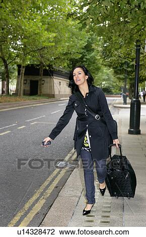 Stock Image - Businesswoman hailing cab. Fotosearch