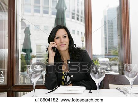 Stock Image - Businesswoman on mobile in restaurant. Fotosearch
