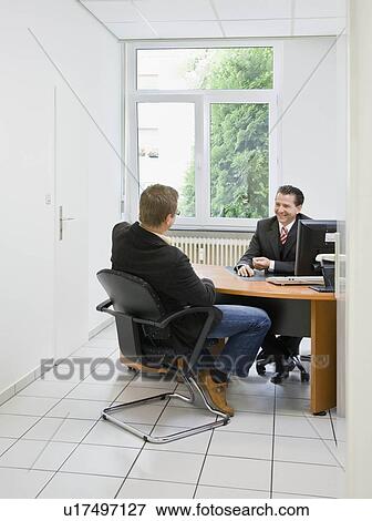 Co-workers at desk in office View Large Photo Image Stock Photo - Co-workers at desk in office. Fotosearch